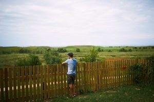 Young tourist looking at green landscape standing a fence